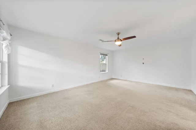 an empty room with a ceiling fan and window