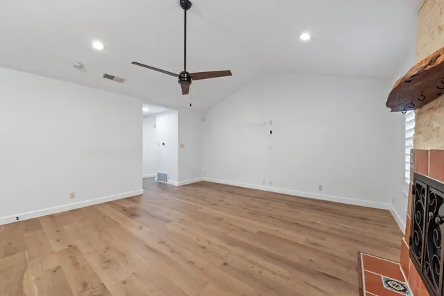 a view of empty room with wooden floor and ceiling fan