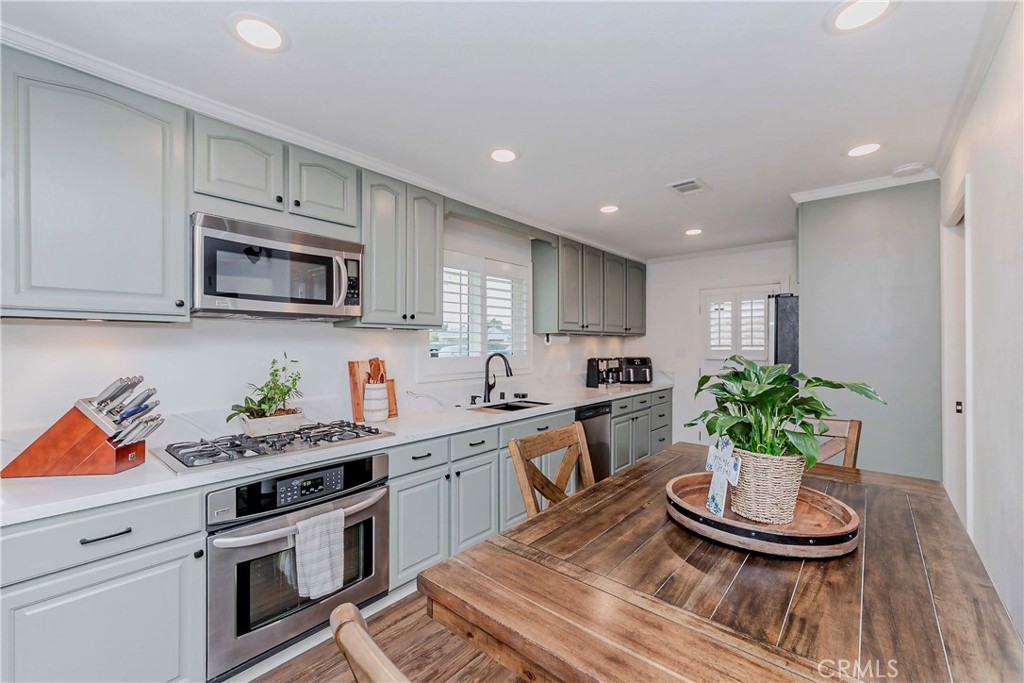 10252 Lorraine Lane Cypress, CA 90630 - Photo 15 of 44 a kitchen with stainless steel appliances kitchen island granite countertop a sink a stove a microwave a dining table and chairs