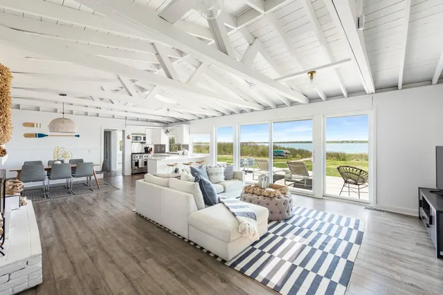 a living room with furniture large windows and wooden floor