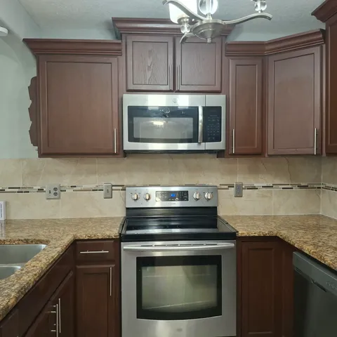 a kitchen with granite countertop a stove microwave and sink