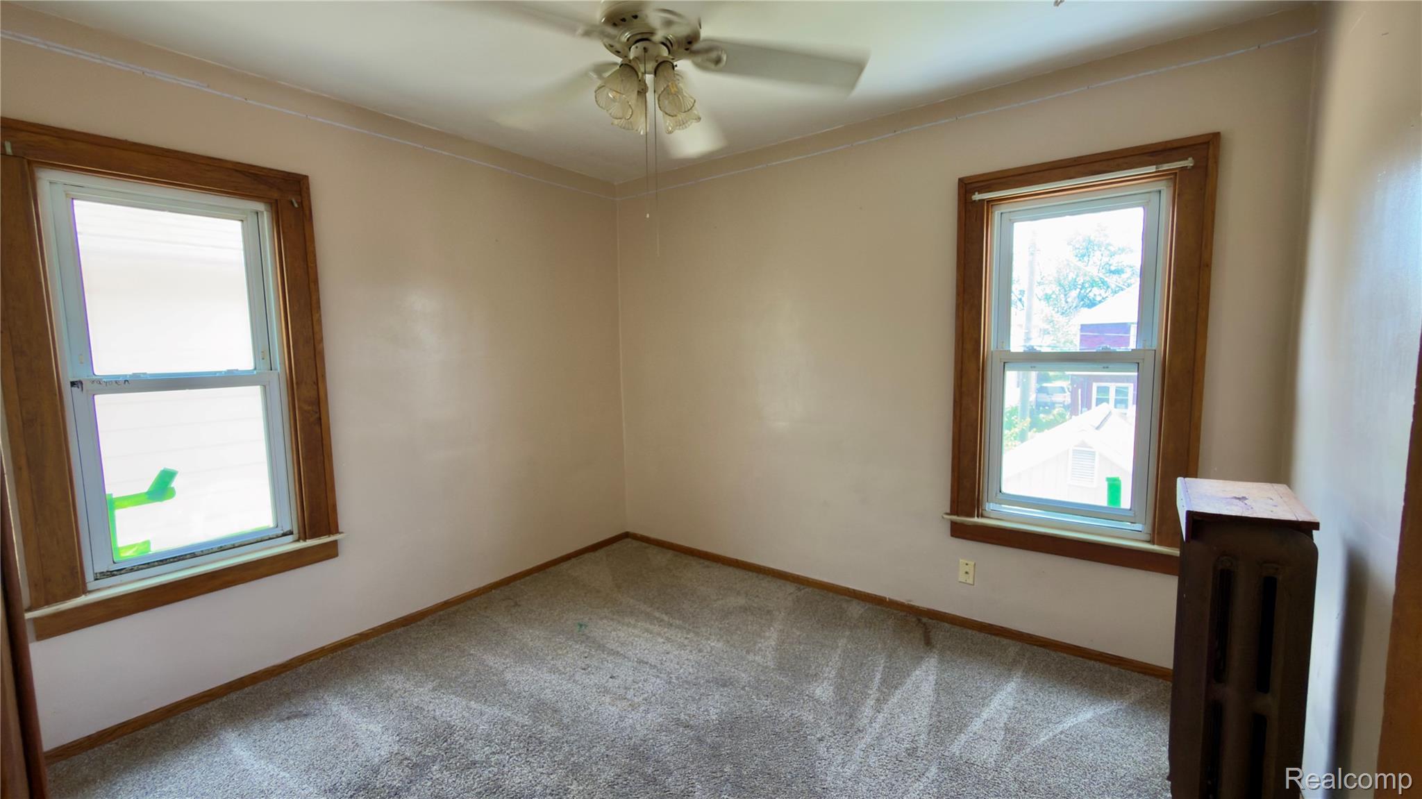 130 Elm Street River Rouge, MI 48218 - Photo 17 of 20 Room featuring two windows with wood-finish trim, neutral-toned walls, and a ceiling fan with light fixture