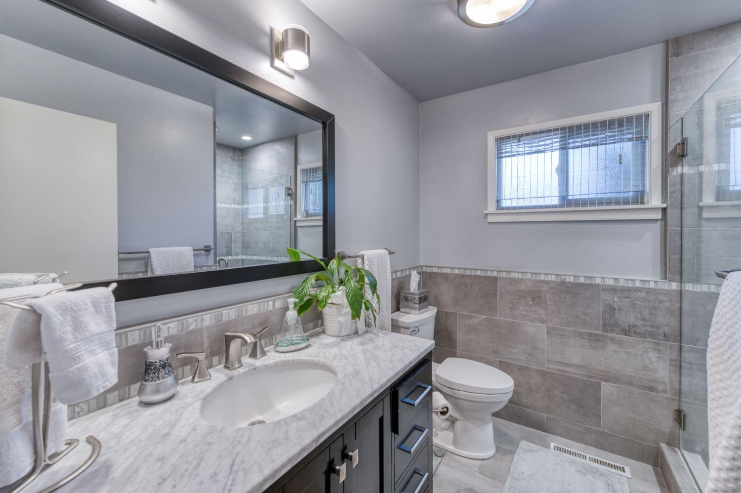 6811 North Backer Avenue Fresno, CA 93710 - Photo 20 of 26 a bathroom with a granite countertop sink a toilet and a mirror