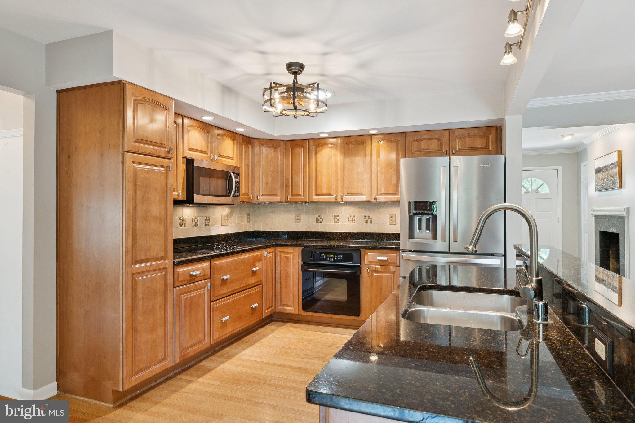 346 Edgewater Road Pasadena, MD 21122 - Photo 5 of 75 a kitchen with stainless steel appliances granite countertop a stove top oven a sink dishwasher and white cabinets with wooden floor
