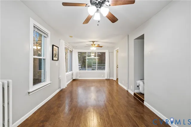 a view of an empty room with wooden floor and a window