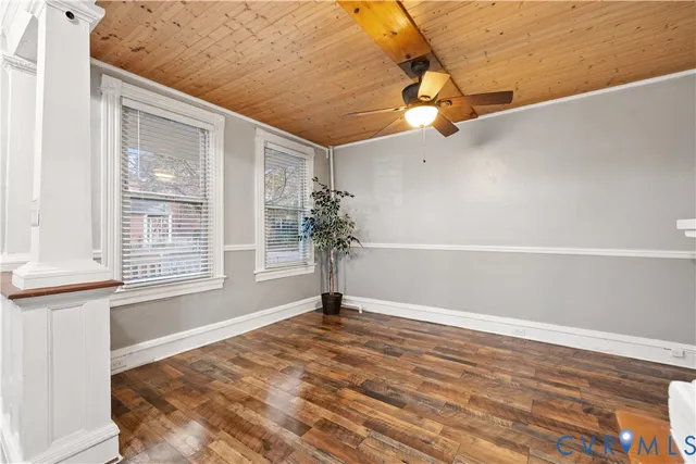 a view of an empty room with a window and wooden floor