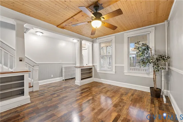a view of an empty room with a window and wooden floor