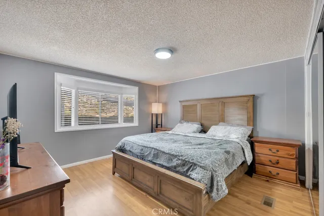 a bedroom with a bed and a flat tv screen on a dresser