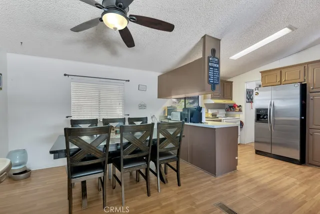 a kitchen with stainless steel appliances kitchen island granite countertop a dining table chairs and a refrigerator