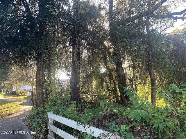 a view of a yard with wooden fence and trees