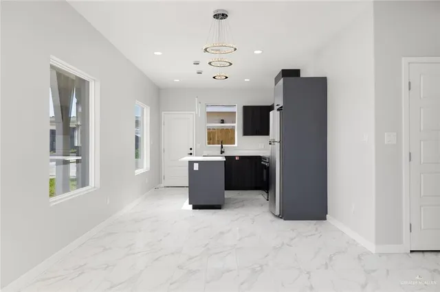 a living room with stainless steel appliances kitchen island granite countertop furniture and a refrigerator