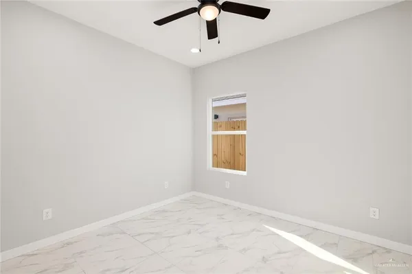 an empty room with windows and chandelier fan