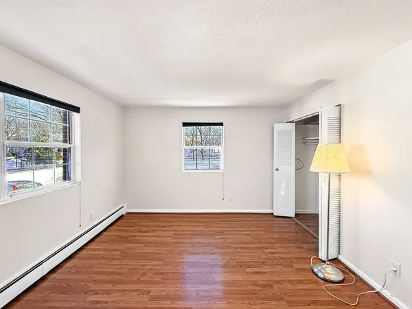 a view of an empty room with a window and wooden floor