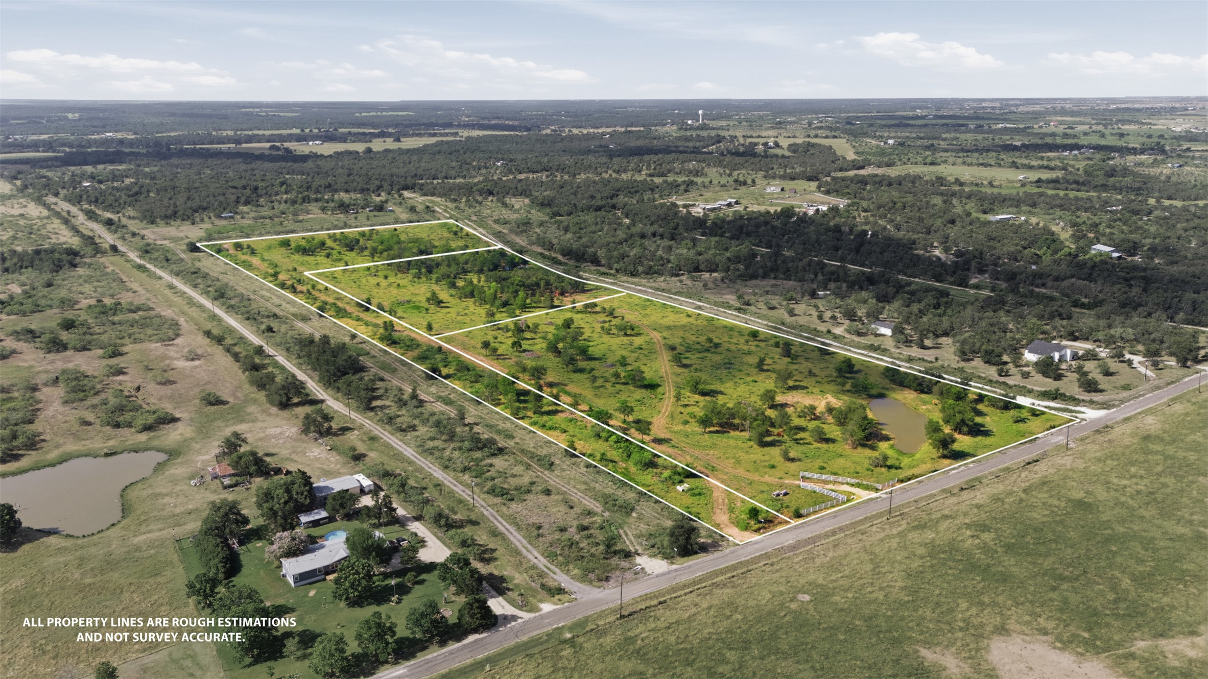 3280 County Road 466 Elgin, TX 78621 - Photo 4 of 13 Expansive acreage provides a verdant canvas for custom development opportunities, bordered by natural tree lines and offering serene water features.