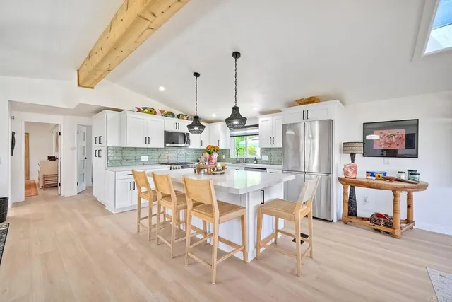 a kitchen with stainless steel appliances kitchen island granite countertop a table chairs and a refrigerator