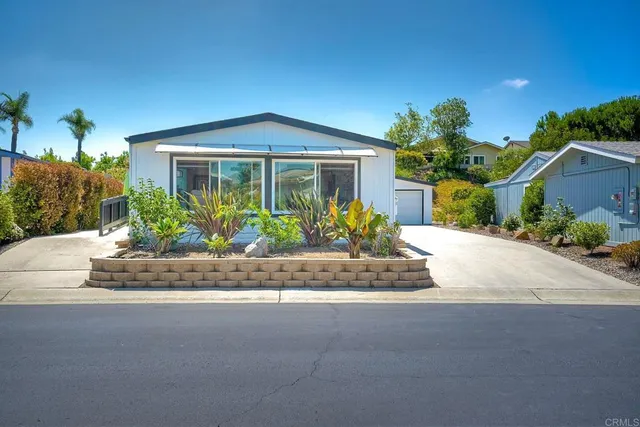 a front view of a house with a yard and potted plants