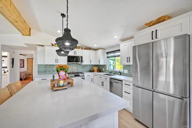 a kitchen with stainless steel appliances granite countertop a refrigerator a oven a sink dishwasher and white cabinets with wooden floor