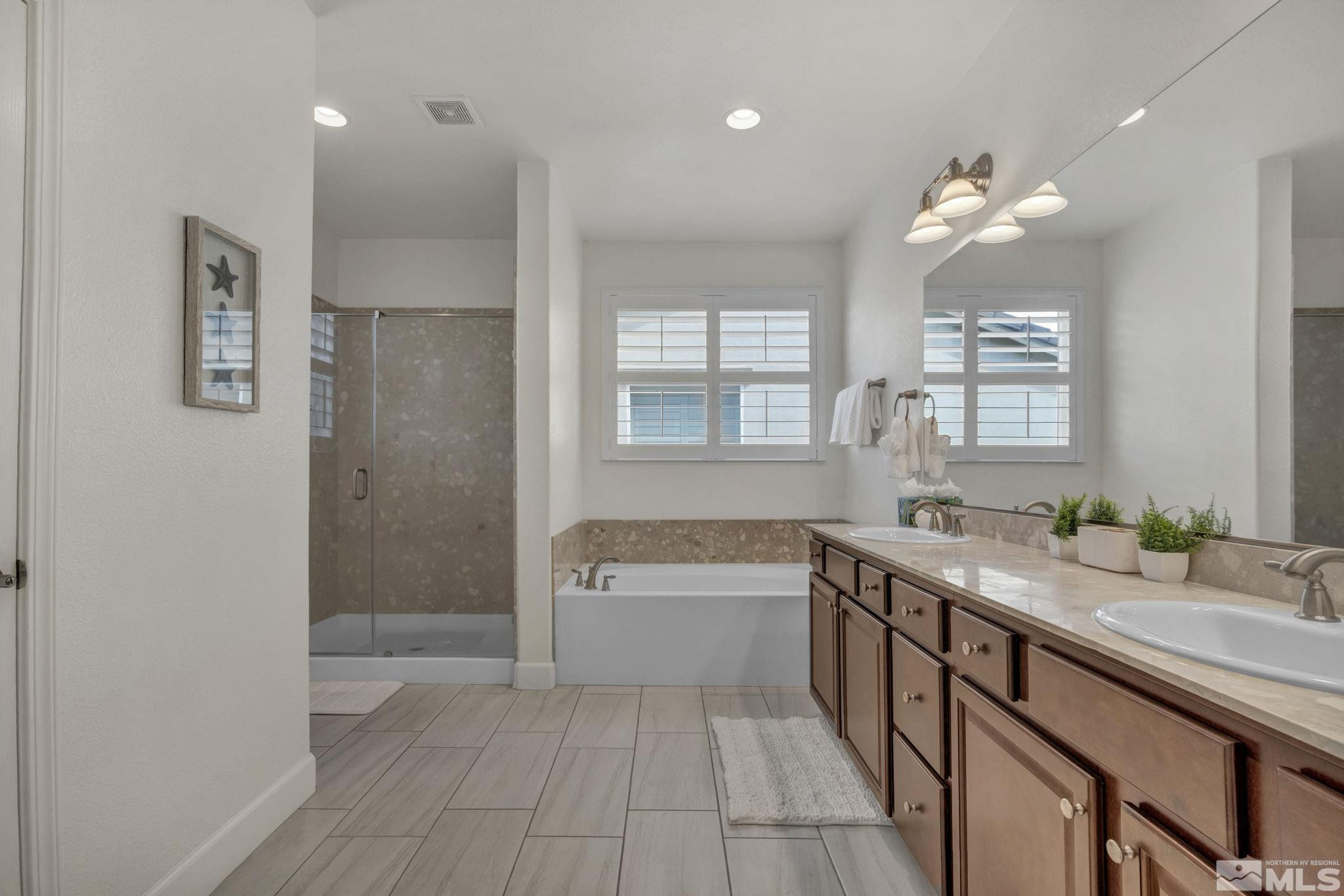 10345 Rollins Drive Reno, NV 89521 - Photo 19 of 39 a bathroom with a granite countertop sink a large mirror and a bathtub
