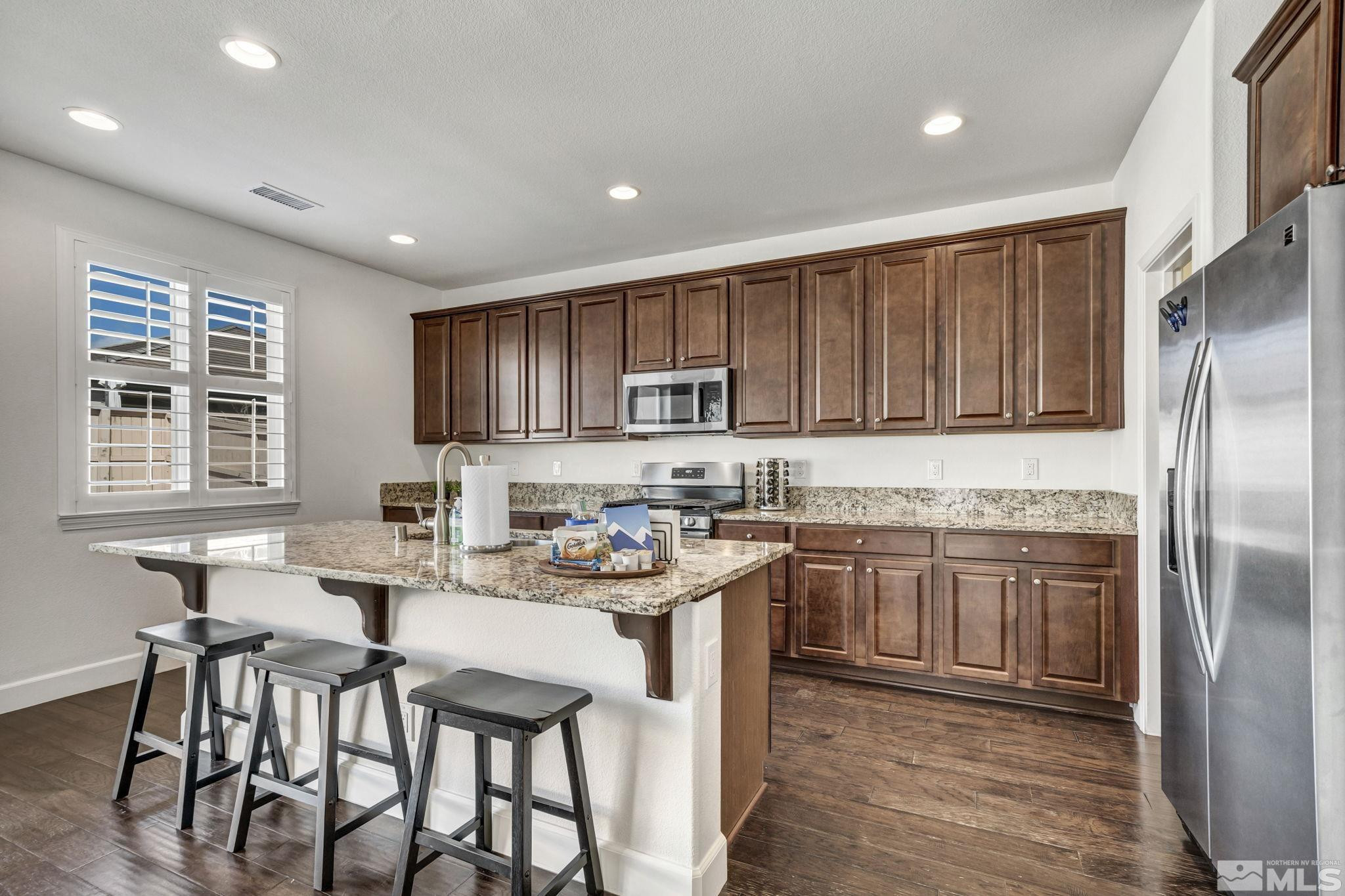 10345 Rollins Drive Reno, NV 89521 - Photo 5 of 39 a kitchen with stainless steel appliances granite countertop a stove a sink a refrigerator and wooden cabinets