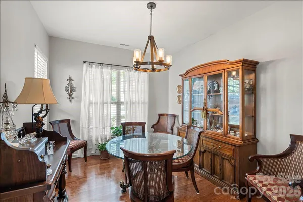 a dining room with furniture a chandelier and wooden floor