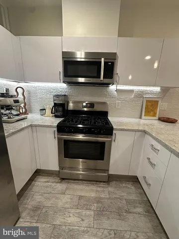 a kitchen with stainless steel appliances granite countertop a refrigerator and a stove