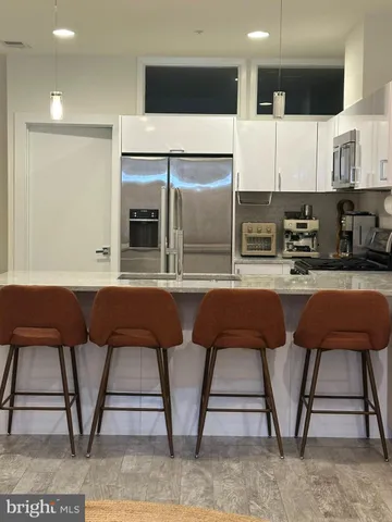 a living room with stainless steel appliances furniture a refrigerator and a sink