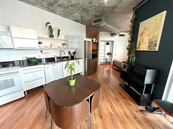 a kitchen with stainless steel appliances granite countertop a sink a stove white refrigerator and cabinets with wooden floor