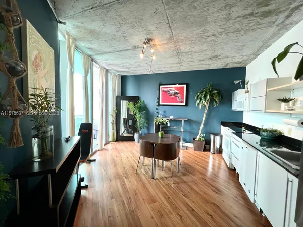 a kitchen with stainless steel appliances granite countertop a stove top oven a sink dishwasher a dining table and chairs with wooden floor