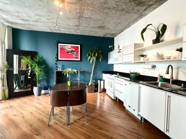 a kitchen with stainless steel appliances granite countertop a stove a sink dishwasher and white cabinets with wooden floor