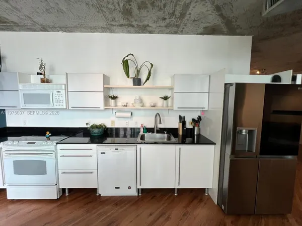 a kitchen with granite countertop white cabinets and white appliances