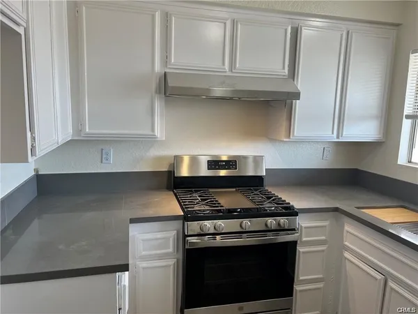 a kitchen with granite countertop white cabinets and stainless steel appliances
