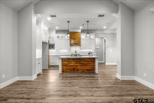 a view of an empty room with wooden floor fireplace and a window