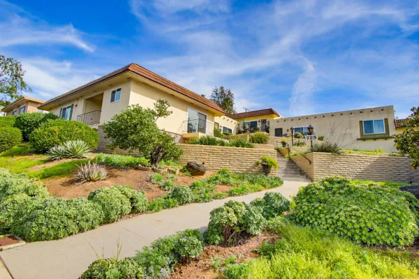 a view of a house with a big yard plants and large trees
