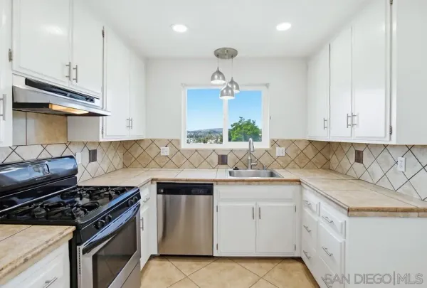 a kitchen with white cabinets and appliances