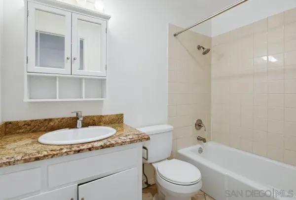 a bathroom with a granite countertop sink toilet a mirror and shower