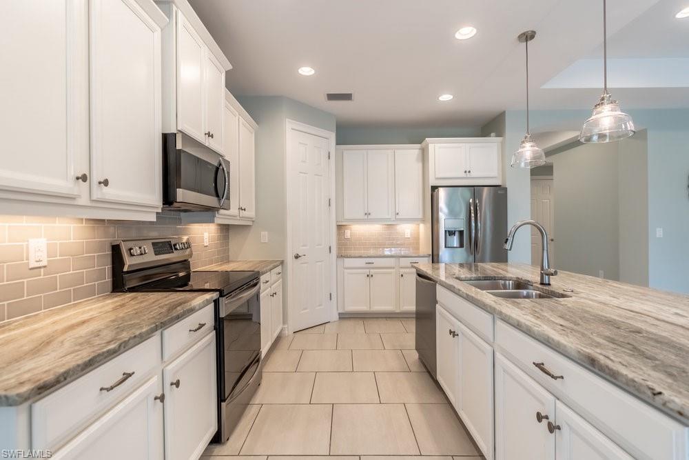 16374 Barclay Court Naples, FL 34110 - Photo 11 of 32 a kitchen with kitchen island granite countertop a sink a counter top space stainless steel appliances and cabinets