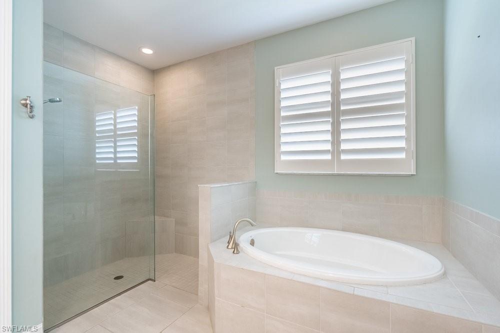 16374 Barclay Court Naples, FL 34110 - Photo 22 of 32 a bathroom with a white bath tub sitting next to a window