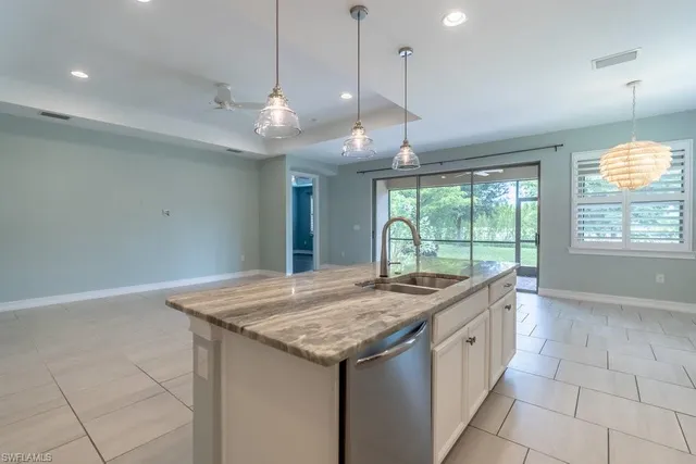 a kitchen with kitchen island granite countertop a sink a counter top space stainless steel appliances and cabinets
