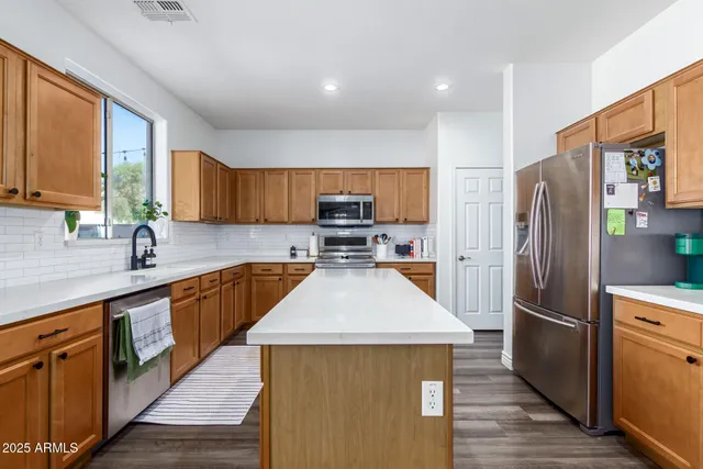 a kitchen with stainless steel appliances granite countertop a refrigerator a sink dishwasher a stove and a oven with wooden floor