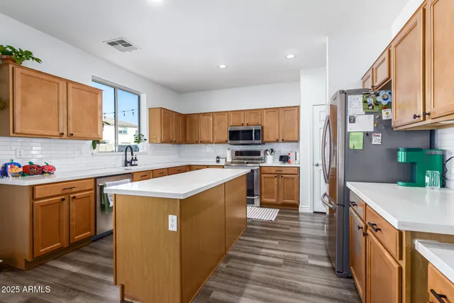 a kitchen with stainless steel appliances granite countertop a stove a sink dishwasher and a refrigerator with wooden floor