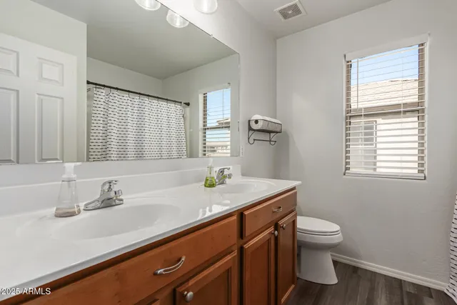 a bathroom with a granite countertop sink a toilet and a window