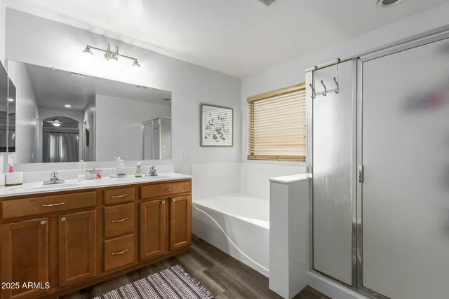 a bathroom with a double vanity sink a large mirror and a bathtub