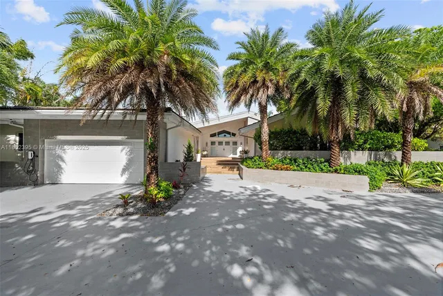 a view of a house with a yard and palm trees