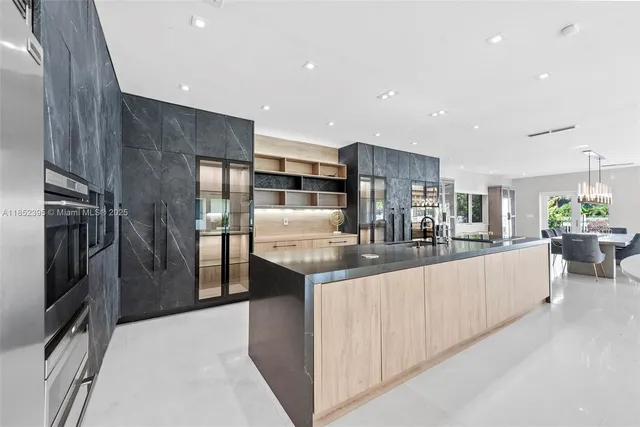 a kitchen with stainless steel appliances kitchen island granite countertop a refrigerator and a sink