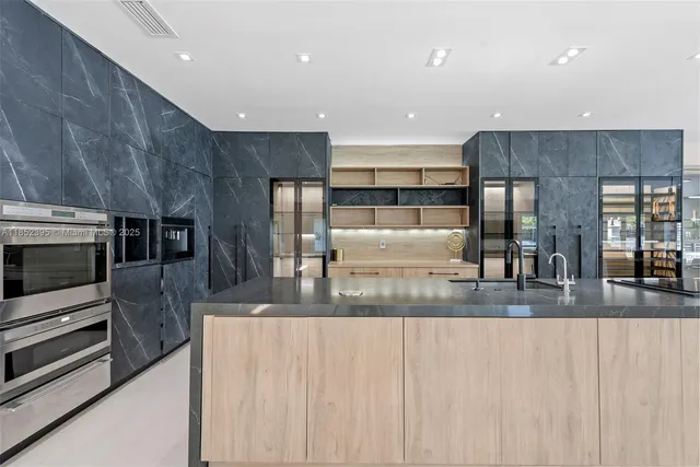 a kitchen with stainless steel appliances granite countertop a refrigerator a stove and a sink