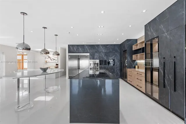 a kitchen with stainless steel appliances kitchen island granite countertop a refrigerator a stove and a sink with wooden floor