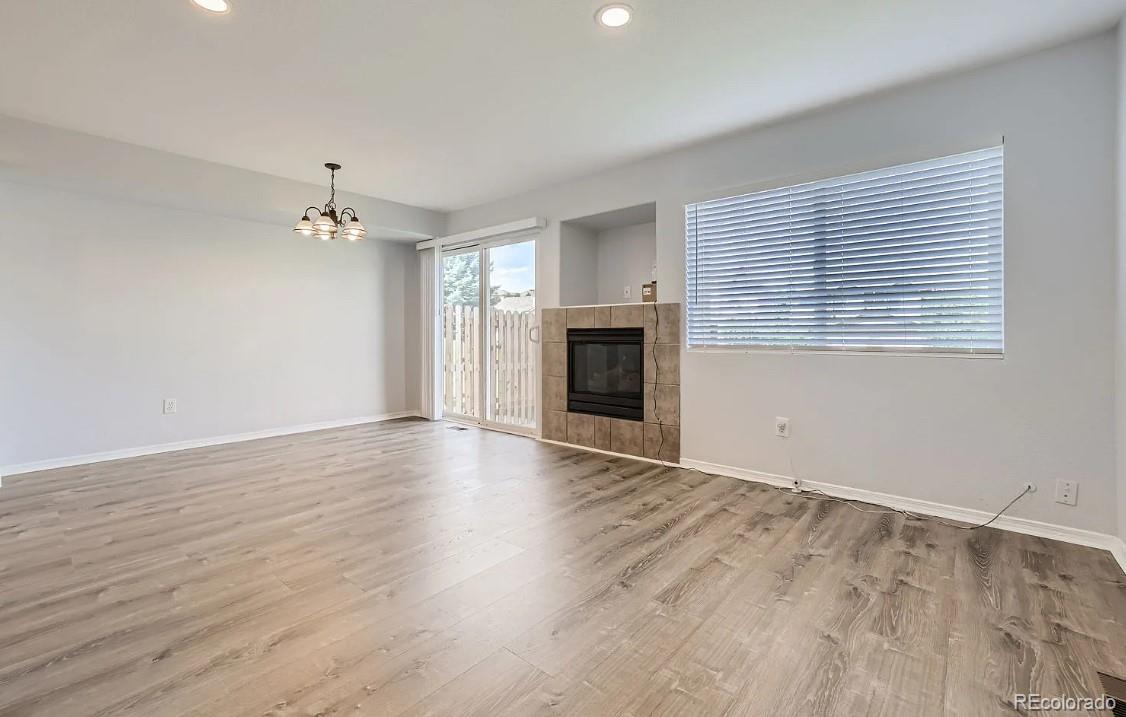 5925-5943 University Village View Colorado Springs, CO 80918 - Photo 5 of 21 an empty room with wooden floor fireplace and windows