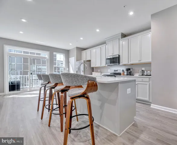 a kitchen with stainless steel appliances granite countertop a stove a sink a refrigerator with a dining table and chairs