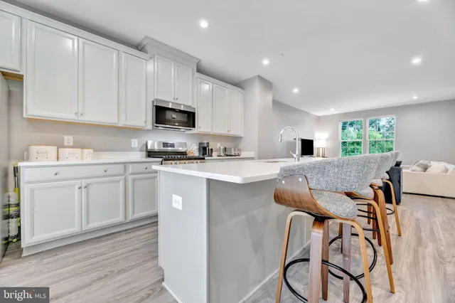 a kitchen with stainless steel appliances granite countertop a stove top oven a sink a refrigerator and white cabinets