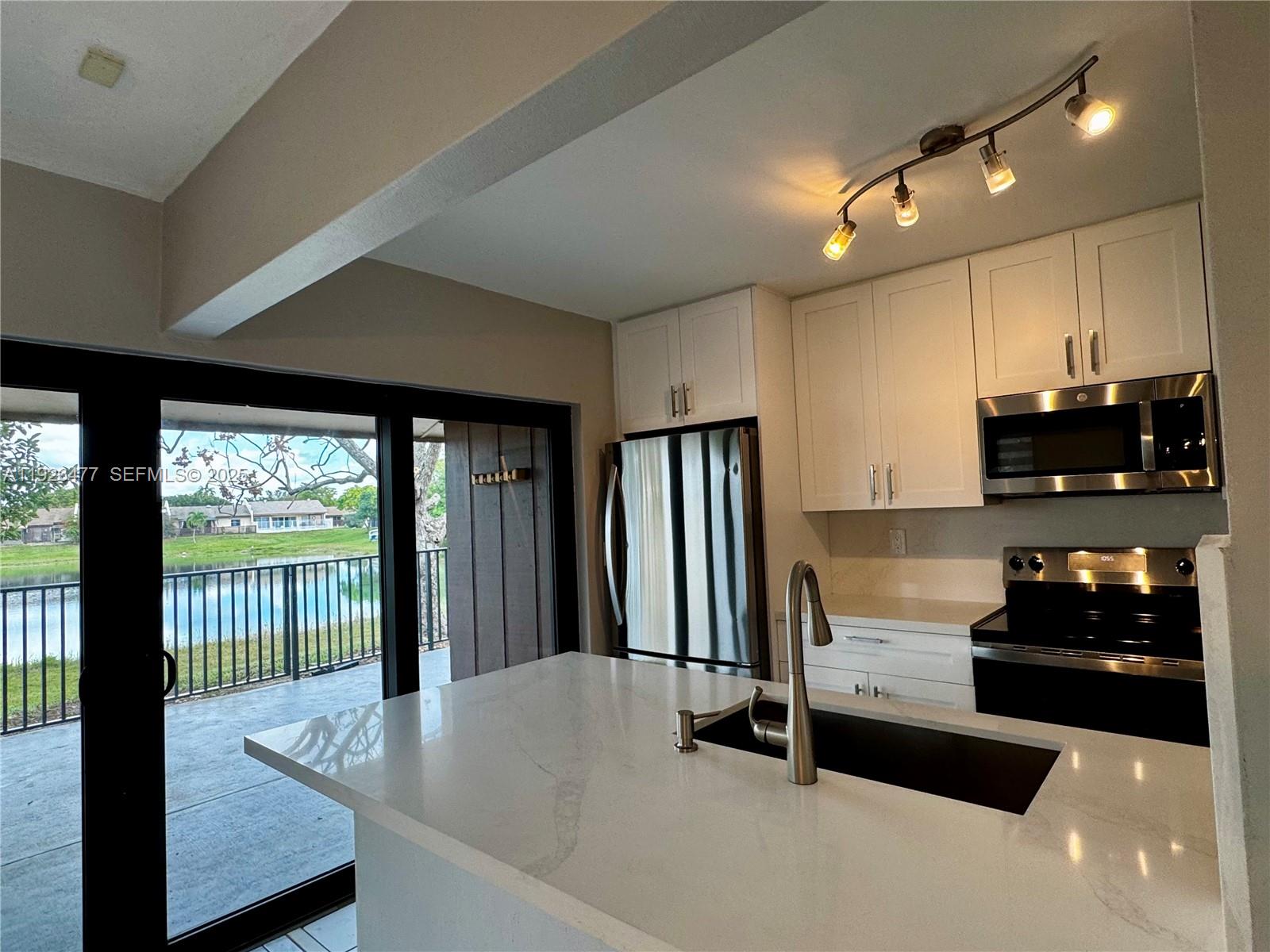 a kitchen with stainless steel appliances granite countertop a refrigerator a stove and a sink with wooden floor